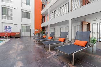 a row of lounge chairs in front of an apartment building